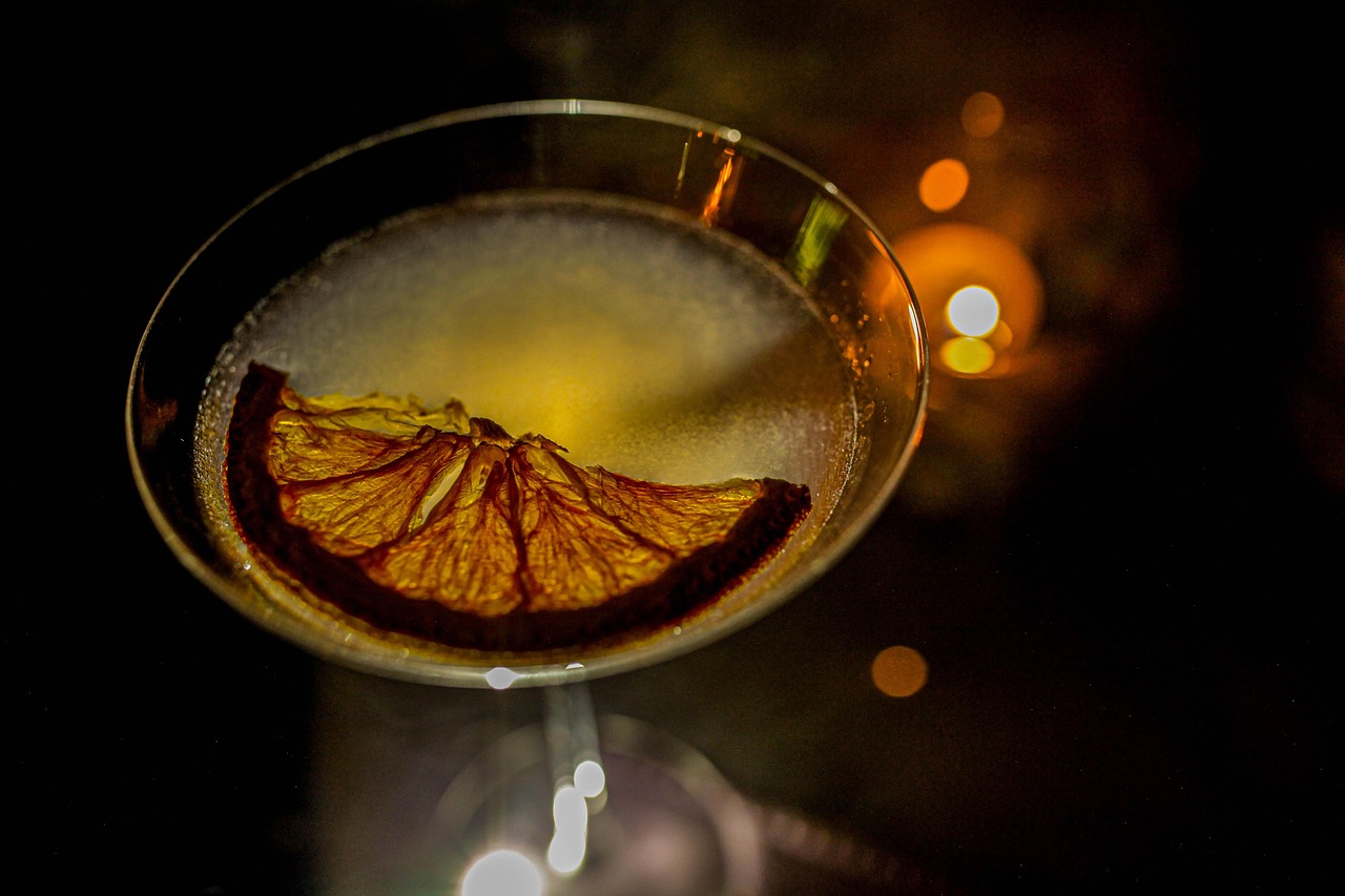 closeup on a martini glass in an indoor setting with a citrusy cocktail and half dehydrated lemon garnish