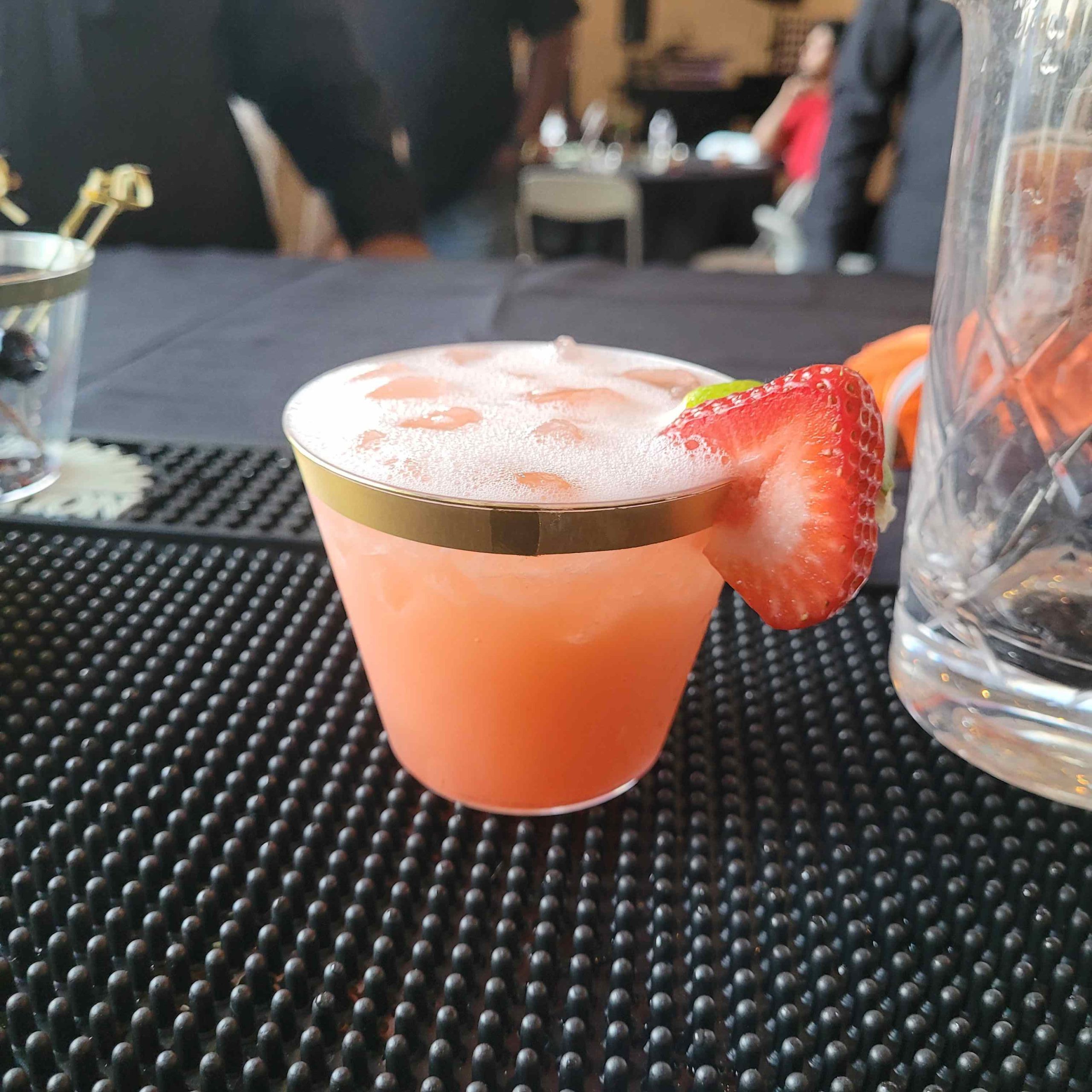 a strawberry daquiri cocktail is displayed on a bar mat before service at a social gathering