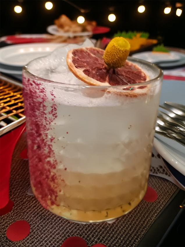 A Tequila based sidecar riff with hibiscus sugar rimming, a dehydrated lemon and a buzz button garnish on a table at night
