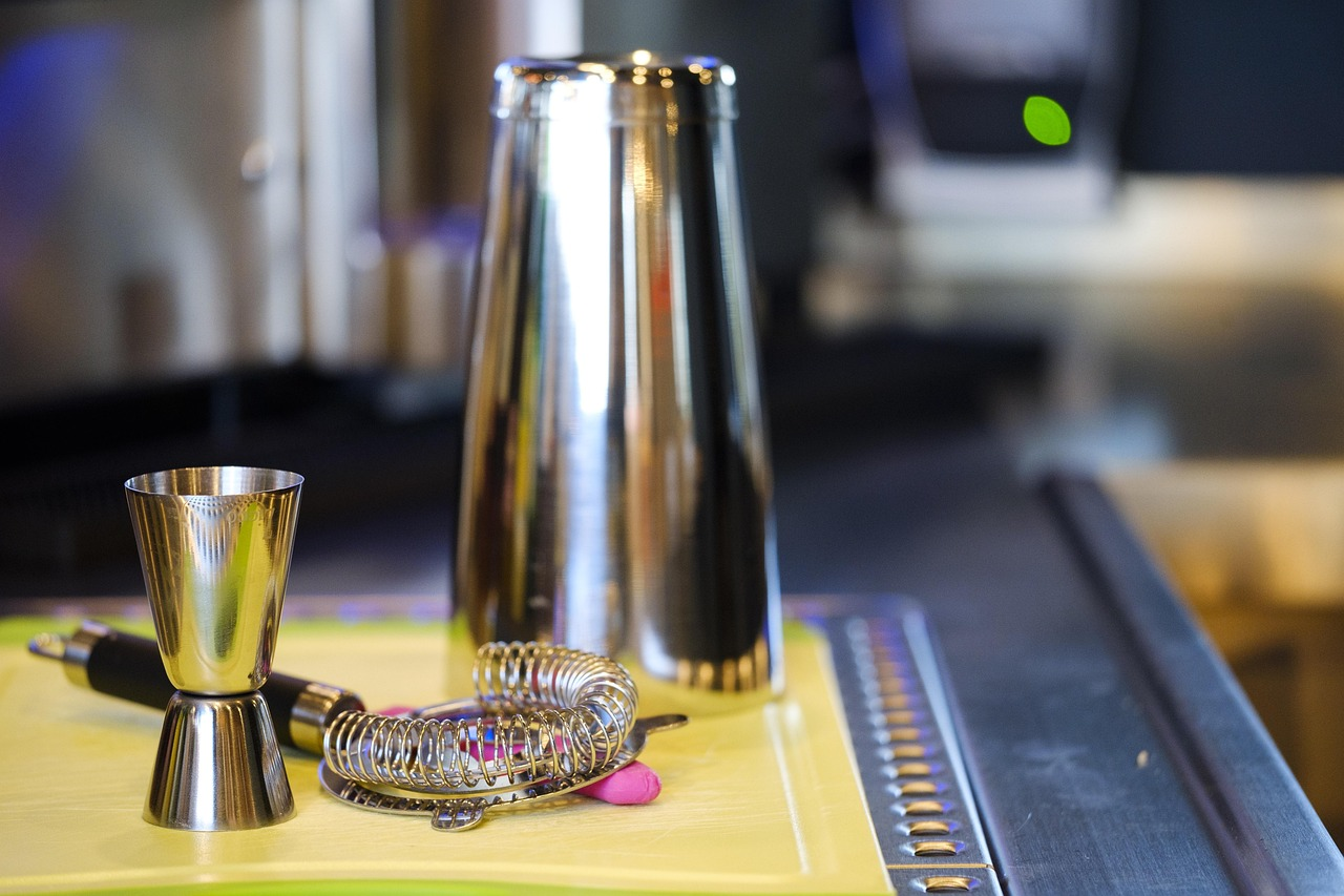 Cocktail shaker jigger and strainer on a cutting board on a bar setting, probably home